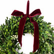 Christmas mistletoe wreath with burgundy bow, decorated with green mistletoe and festive ribbon, perfect for holiday decor.