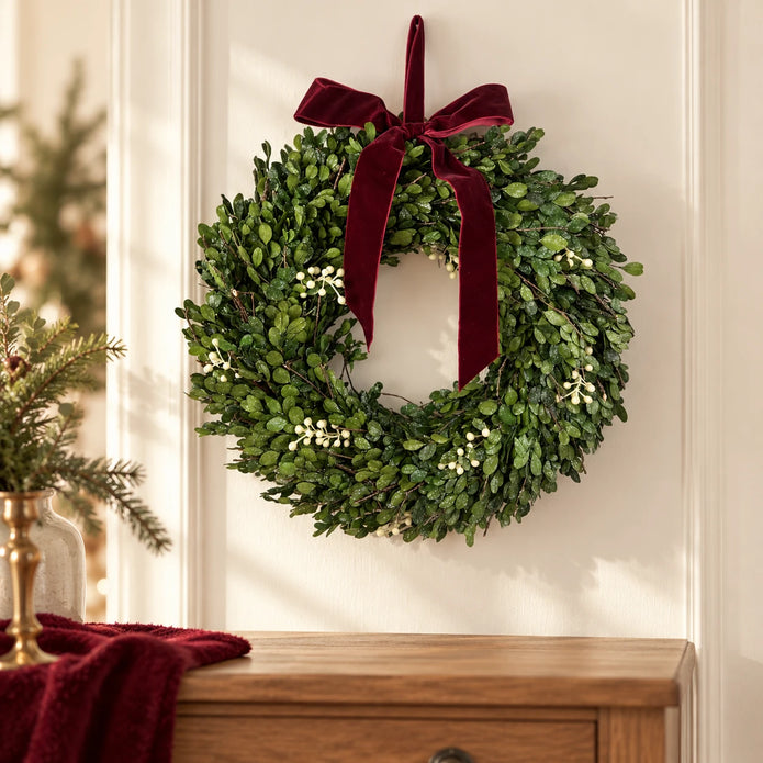 Burgundy bow mistletoe wreath above an oak chest