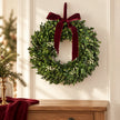 Burgundy bow mistletoe wreath above an oak chest