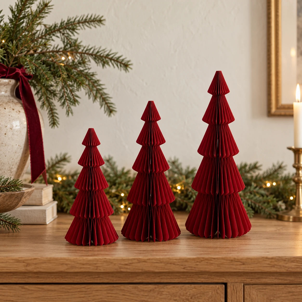 Three burgundy red standing paper trees in 20cm, 25cm and 30cm heights on an oak Christmas sideboard.