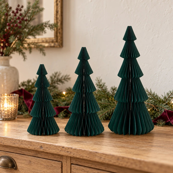 Three dark green standing paper trees in 20cm, 25cm and 30cm heights on an oak Christmas sideboard.