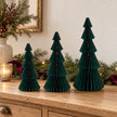 Three dark green standing paper trees in 20cm, 25cm and 30cm heights on an oak Christmas sideboard.