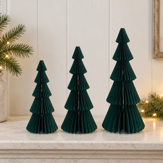 Mixed-size green standing paper trees side by side on a stone mantel.