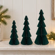 Mixed-size green standing paper trees side by side on a stone mantel.
