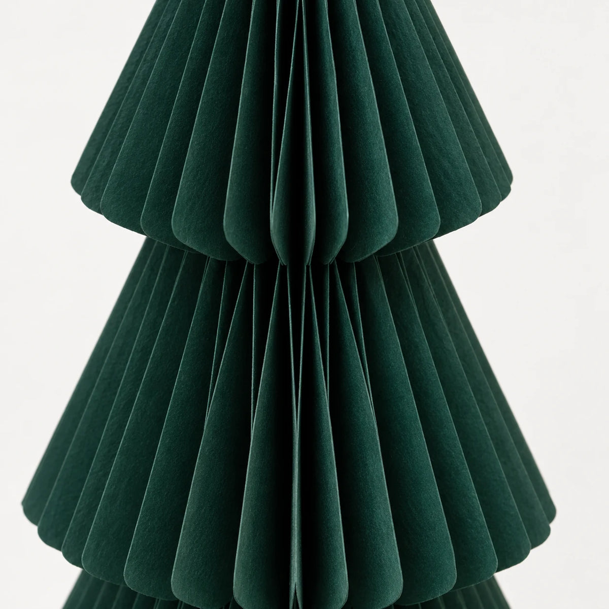 Close-up of dark green folded paper and tier edges on a standing Christmas tree.