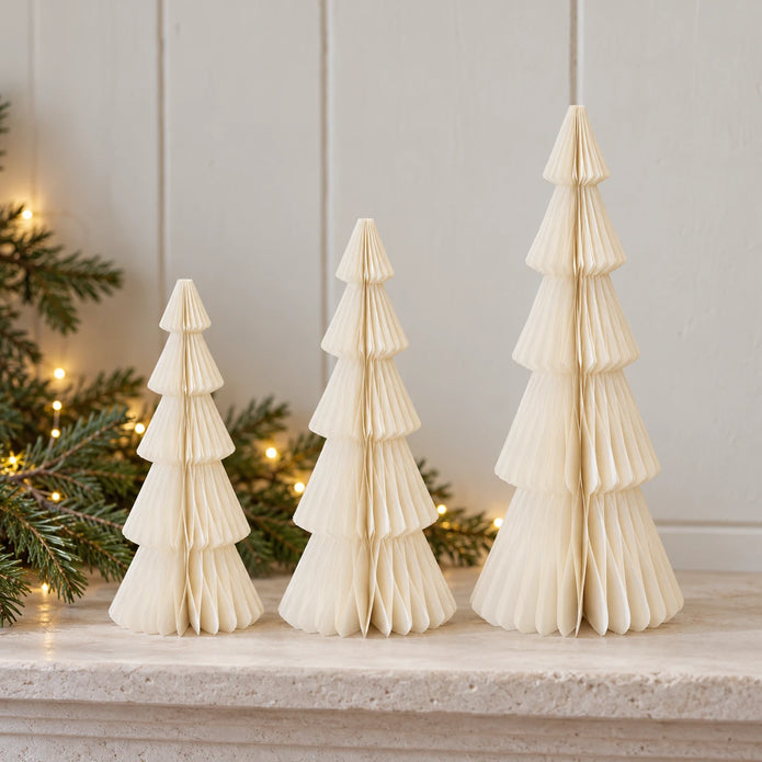 Mixed-size winter white standing paper trees side by side on a stone mantel.