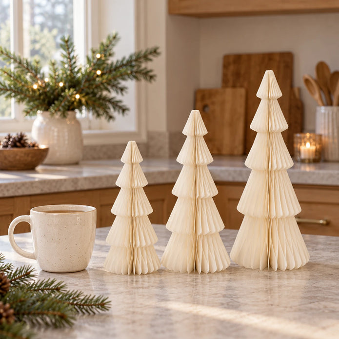 winter white paper tree set in three heights beside a mug of tea in a country kitchen.