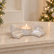 Natural ceramic bow candle holder with a lit tealight on a stone mantel