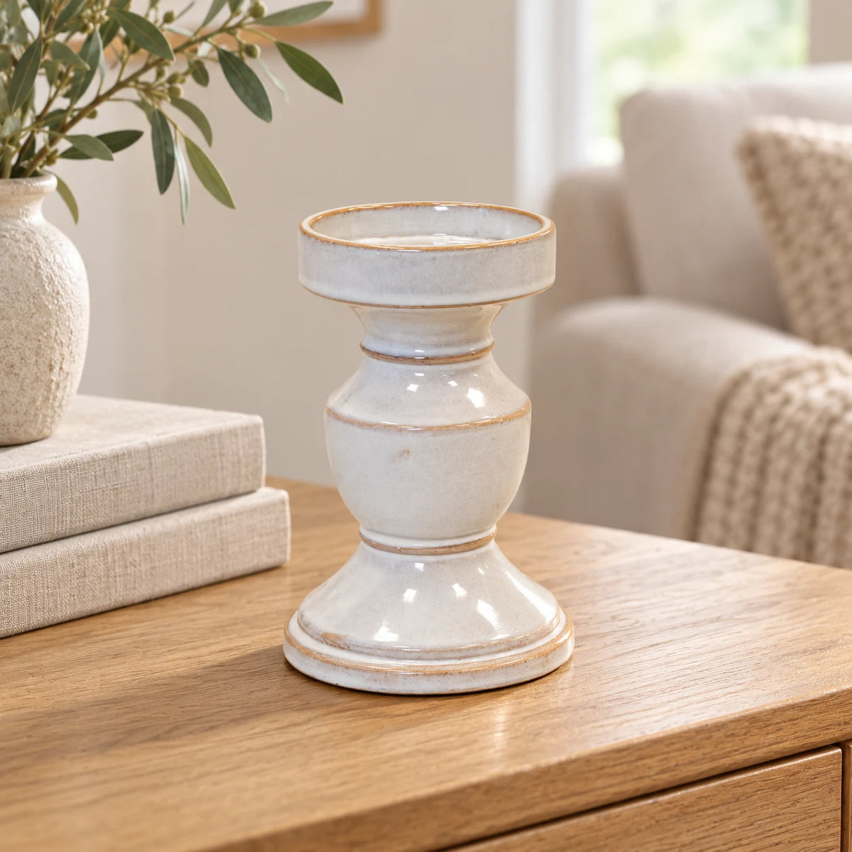 Natural ceramic pedestal candle holder displayed empty beside neutral books