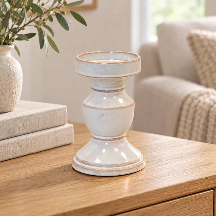 Natural ceramic pedestal candle holder displayed empty beside neutral books