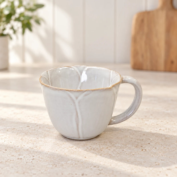 Natural ceramic flower-detail cup on a pale stone kitchen counter