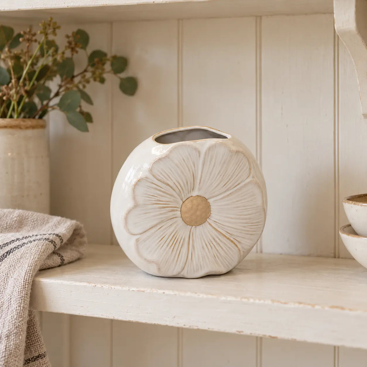 Natural ceramic flower vase by Satchville, featuring a textured design, displayed on a kitchen shelf with decorative flowers.