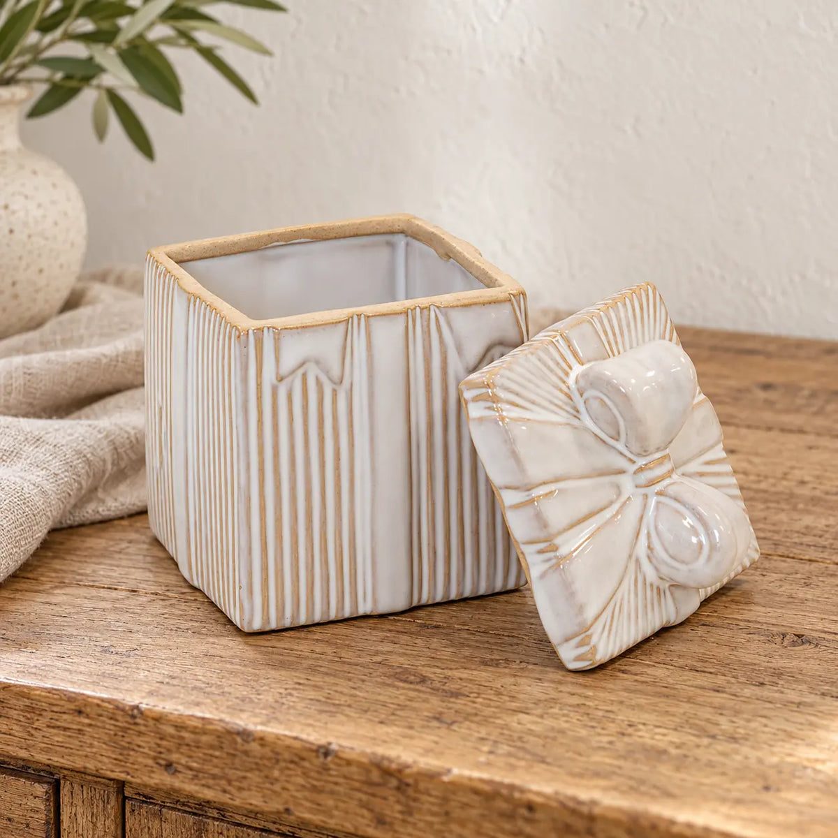 Cream glazed ceramic gift box displayed open on a rustic wooden sideboard