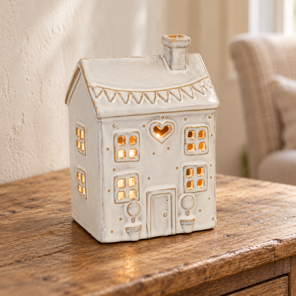 Natural ceramic heart house tealight holder glowing on an aged oak console