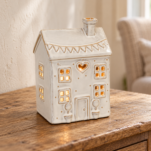 Natural ceramic heart house tealight holder glowing on an aged oak console
