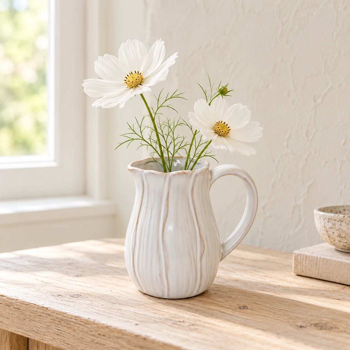 Small natural ceramic jug styled with white faux cosmos on an oak console