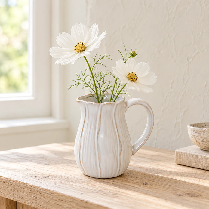 Small natural ceramic jug styled with white faux cosmos on an oak console