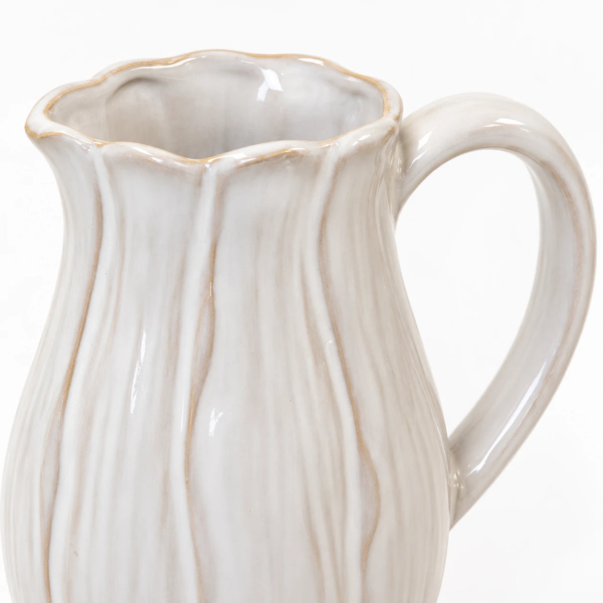 Close-up of the small jug's scalloped beige-edged rim, petal contours and curved handle
