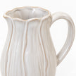Close-up of the small jug's scalloped beige-edged rim, petal contours and curved handle