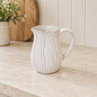 Small natural ceramic petal-shaped jug on a pale limestone kitchen counter
