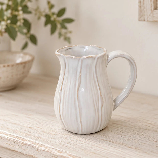 Small white ceramic petal vase by Satchville, featuring a delicate petal design, displayed on a shelf.