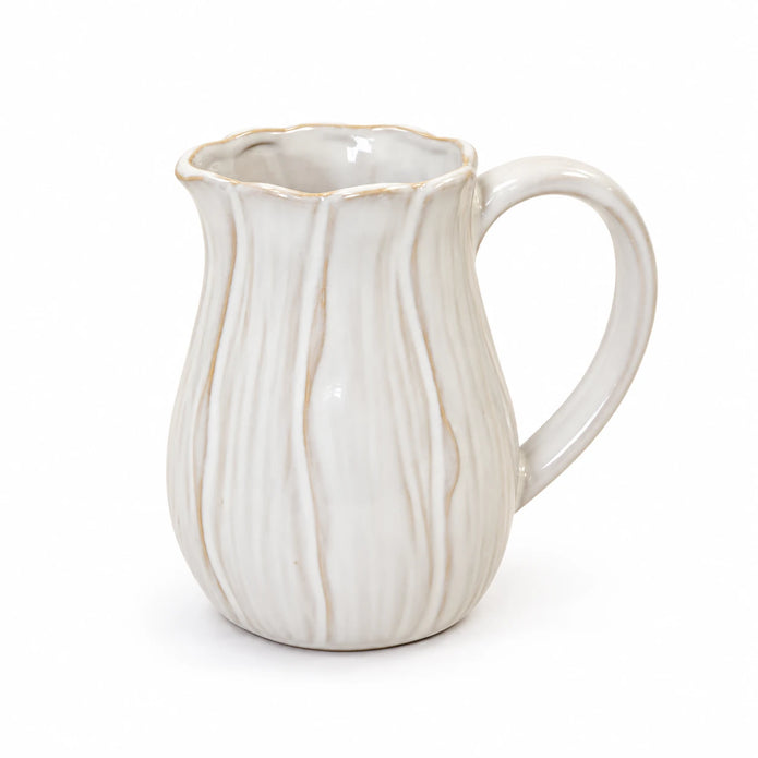 Small natural ceramic jug with wavy petal contours and scalloped rim on a white background