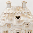 White studio close-up of the ceramic cottage's textured thatch roof, two chimneys and heart-shaped opening.