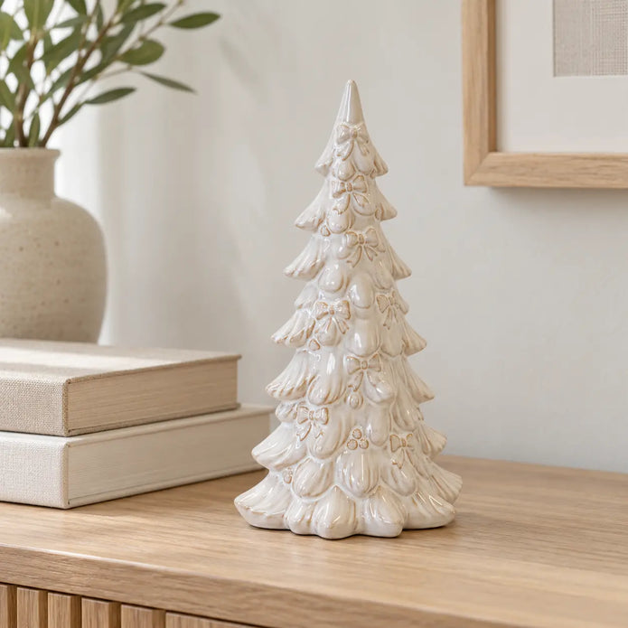 Small natural glazed layered Christmas tree on an oak console beside books.
