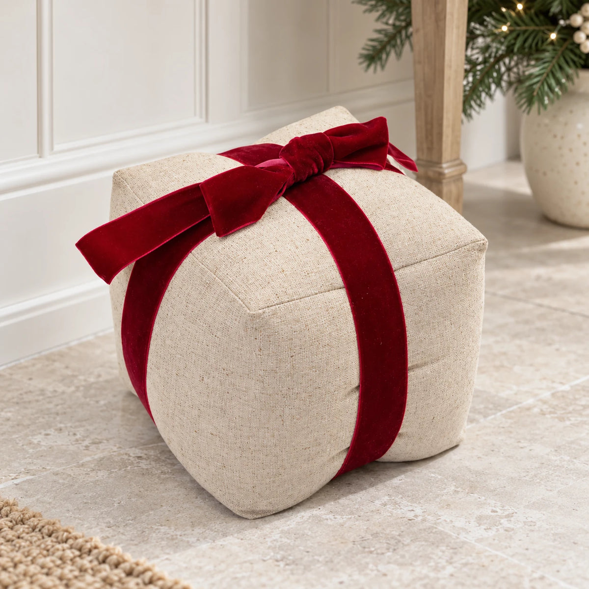 Present-shaped natural linen doorstop styled in a neutral hallway with Christmas greenery