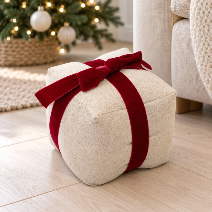 Natural linen Christmas present doorstop with red bow beside a cream sofa