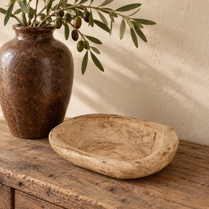 Pale natural pine mini dough bowl styled empty on an oak console beside a tall brown ceramic vase.