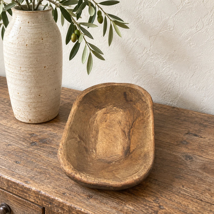 Natural walnut mini dough bowl styled empty on a wooden console beside a tall cream vase.