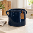 Empty navy blue stoneware pot with twin handles on a light country kitchen counter