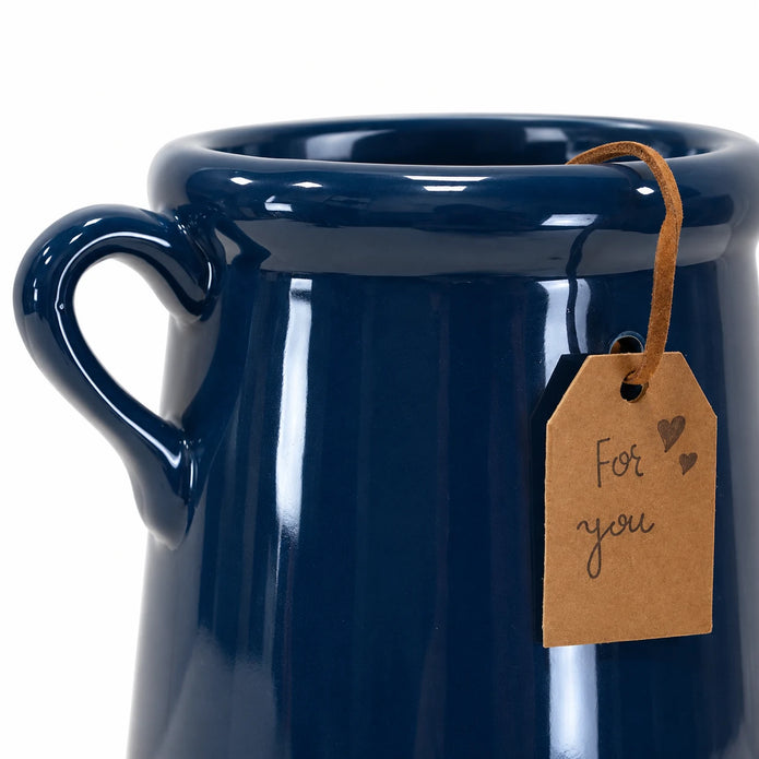Close-up of the navy glazed stoneware vase showing its rolled rim, curved handle and brown For you tag.