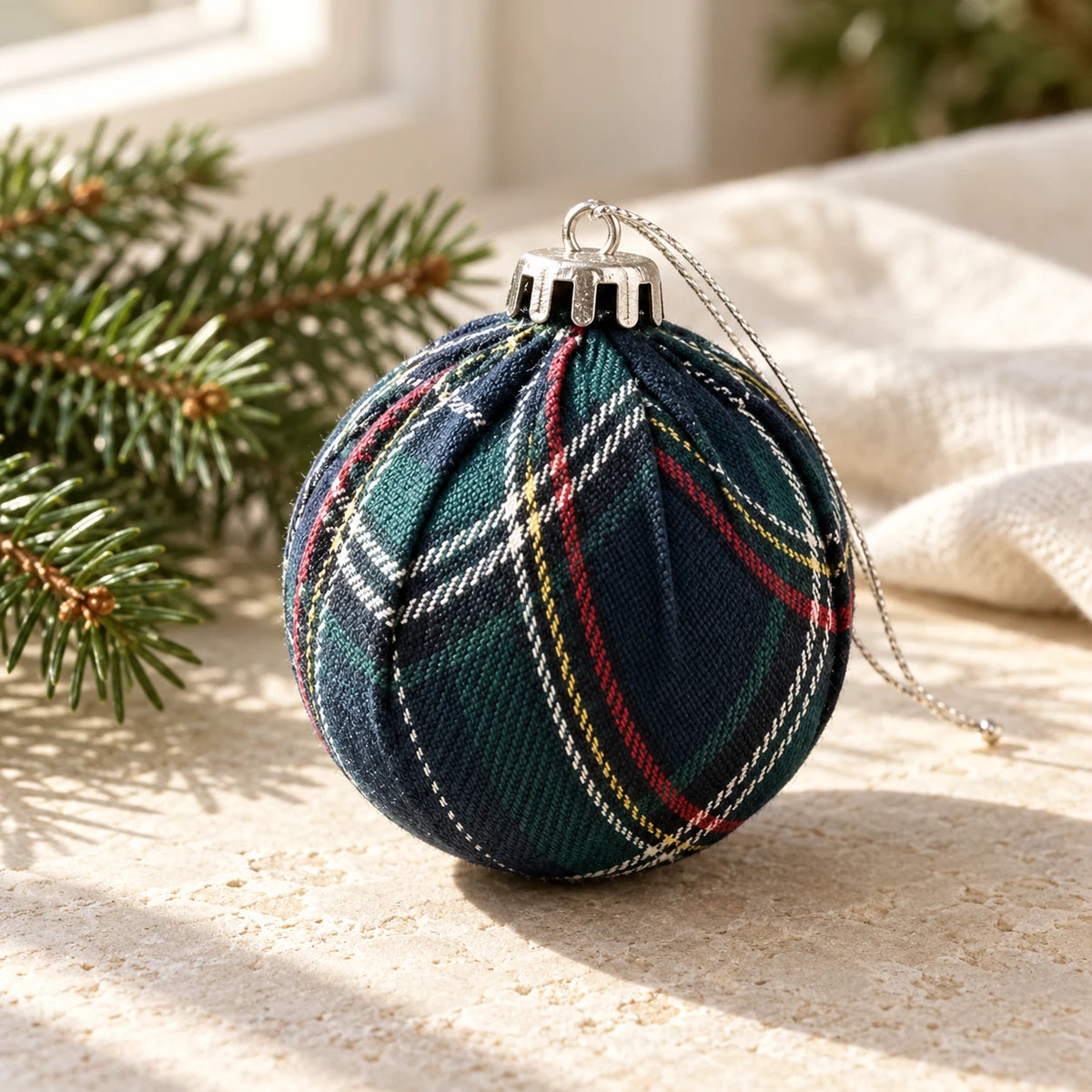 Navy blue tartan Christmas bauble from Starlight Express, hanging on a decorated Christmas tree.