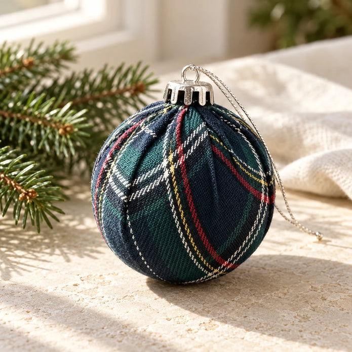 Navy blue tartan Christmas bauble from Starlight Express, hanging on a decorated Christmas tree.