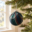 Navy blue tartan Christmas bauble from Starlight Express hanging in a window for holiday decor.