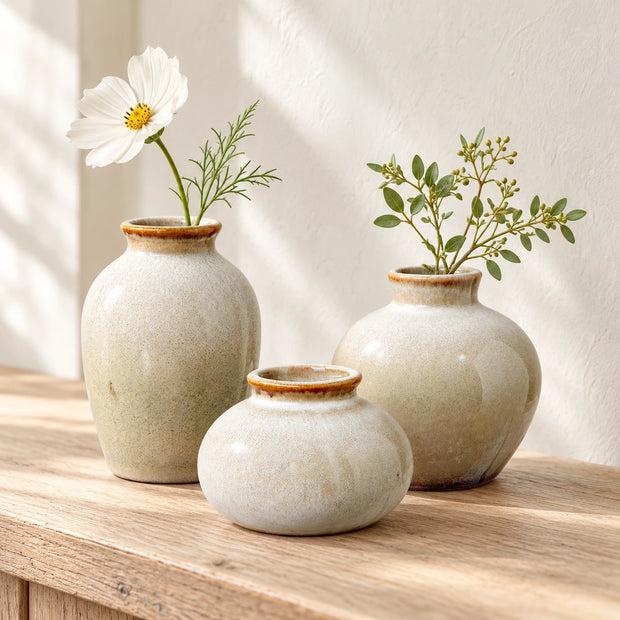 Three neutral ceramic mini bud vase sizes styled together on pale oak for comparison; each size is sold separately.