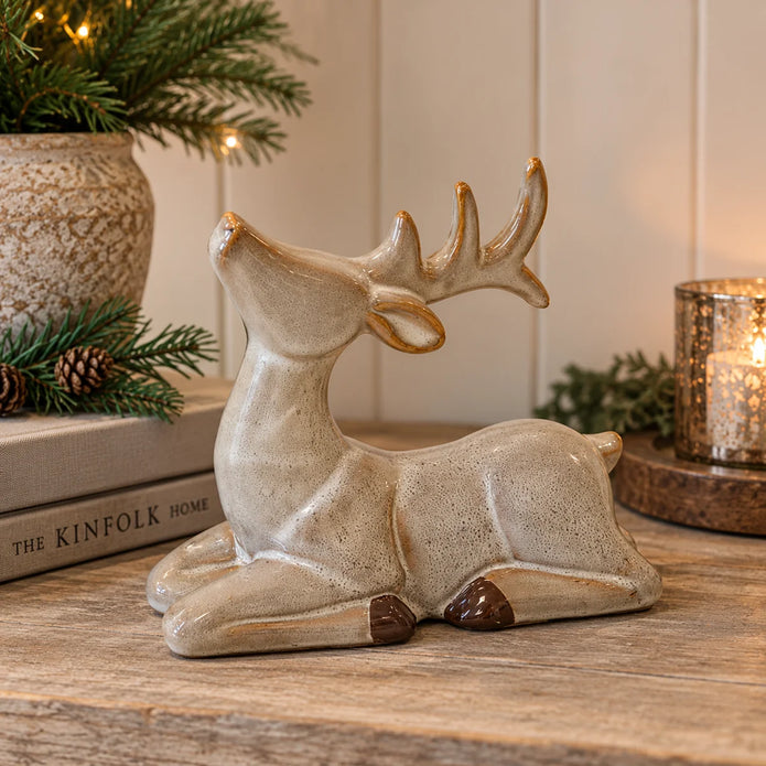 Fawn glazed sitting ceramic reindeer with brown hooves styled on a festive country home shelf