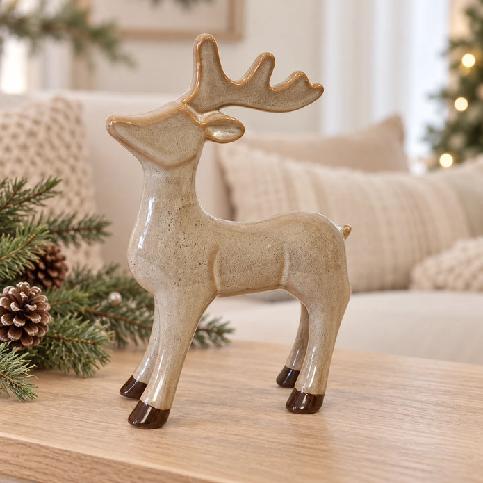 Neutral fawn glazed ceramic standing reindeer on an oak console with Christmas greenery.