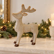 Standing ceramic reindeer ornament with brown hooves on a cream Christmas mantel.