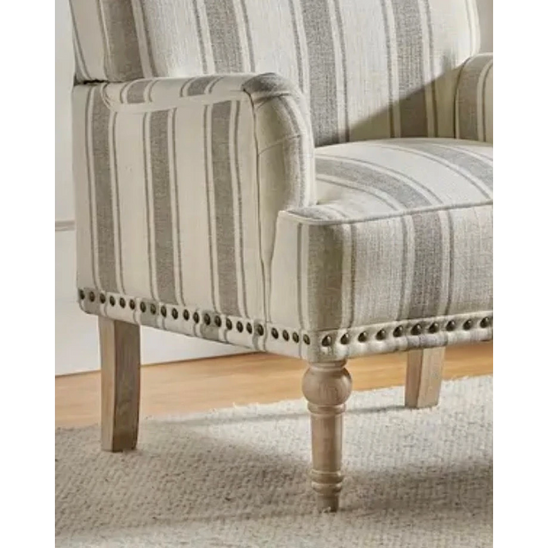 Close view of the beige striped armchair's arm, seat, nailhead trim and front wooden leg.
