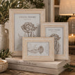 Pale natural wooden Isla picture frames grouped with greenery, books and candle in a neutral home