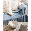 Ocean Blue Diamond Pattern Knitted Throw, blue knitted throw beside cream cushions and a book