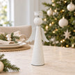 Tall off-white metal angel tealight holder styled empty on a neutral Christmas dining table.