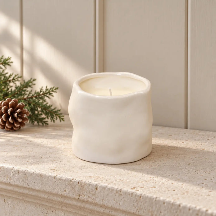 Off-white Satchville sculpted candle for home decor, featuring intricate carved design on a mantel display.