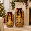 Medium and large oval bamboo lanterns with burgundy bow styling beside a Christmas fireplace