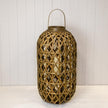 Oval bamboo lantern with a woven lattice, arched handle and glass insert on a white panelled shelf
