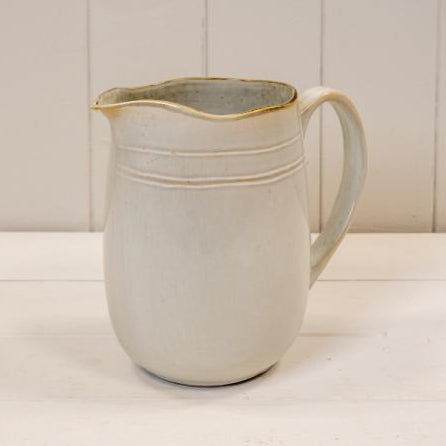 Cream stoneware jug with a curved handle, pouring lip and fine horizontal bands near the rim