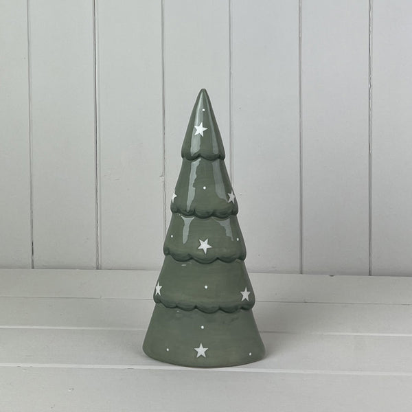 Glazed green ceramic Christmas tree with scalloped branches, white stars and dots against a pale panelled wall